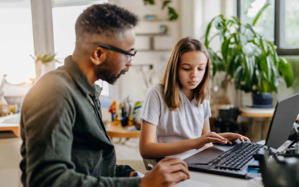 father and teenage daughter fixing software on a computer